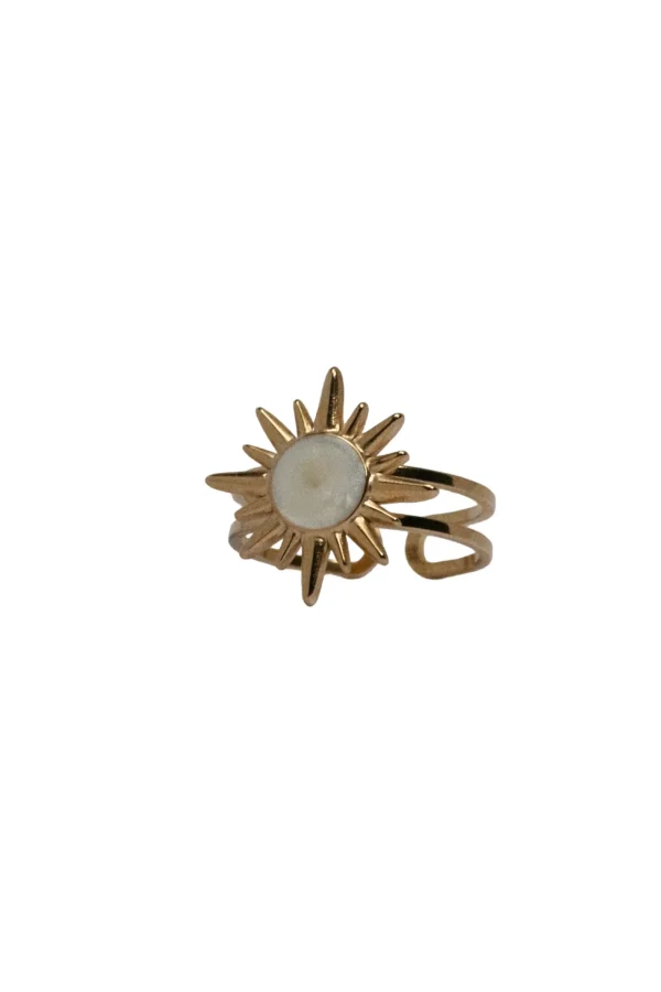 Anillo Nay Sol Anillo ajustable de acero dorado con forma de sol y centro blanco modelo Nay en mano de mujer.