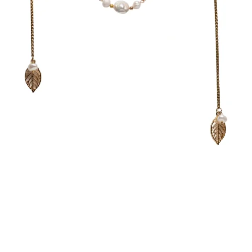 Collar largo tipo corbatero modelo Alma dorado con dijes de hojas y perlas sobre modelo.