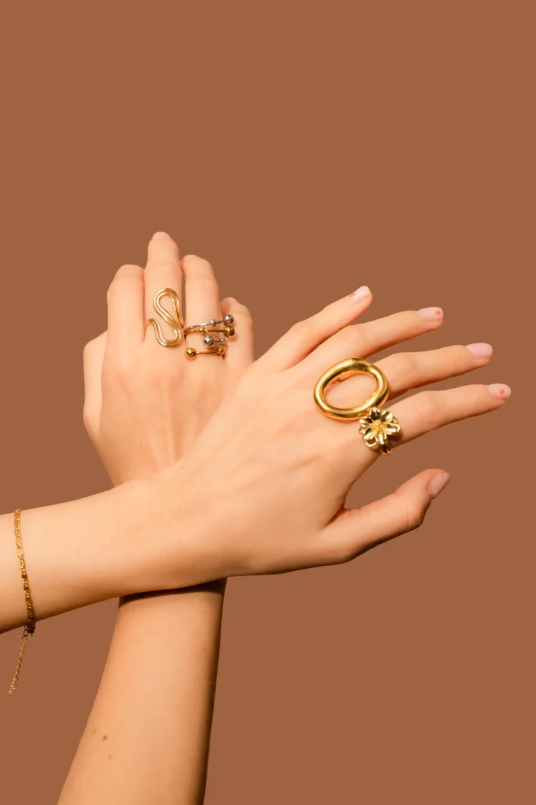 Primer plano de manos femeninas luciendo un conjunto de anillos dorados de diseños variados, incluyendo el anillo Josephine y diseños circulares.
