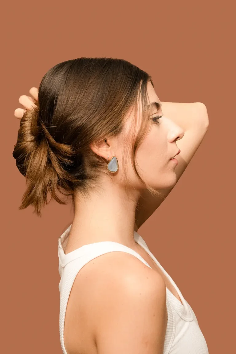 Perfil de modelo con peinado recogido luciendo arracadas Aurora con piedra de cuarzo natural y montura dorada.