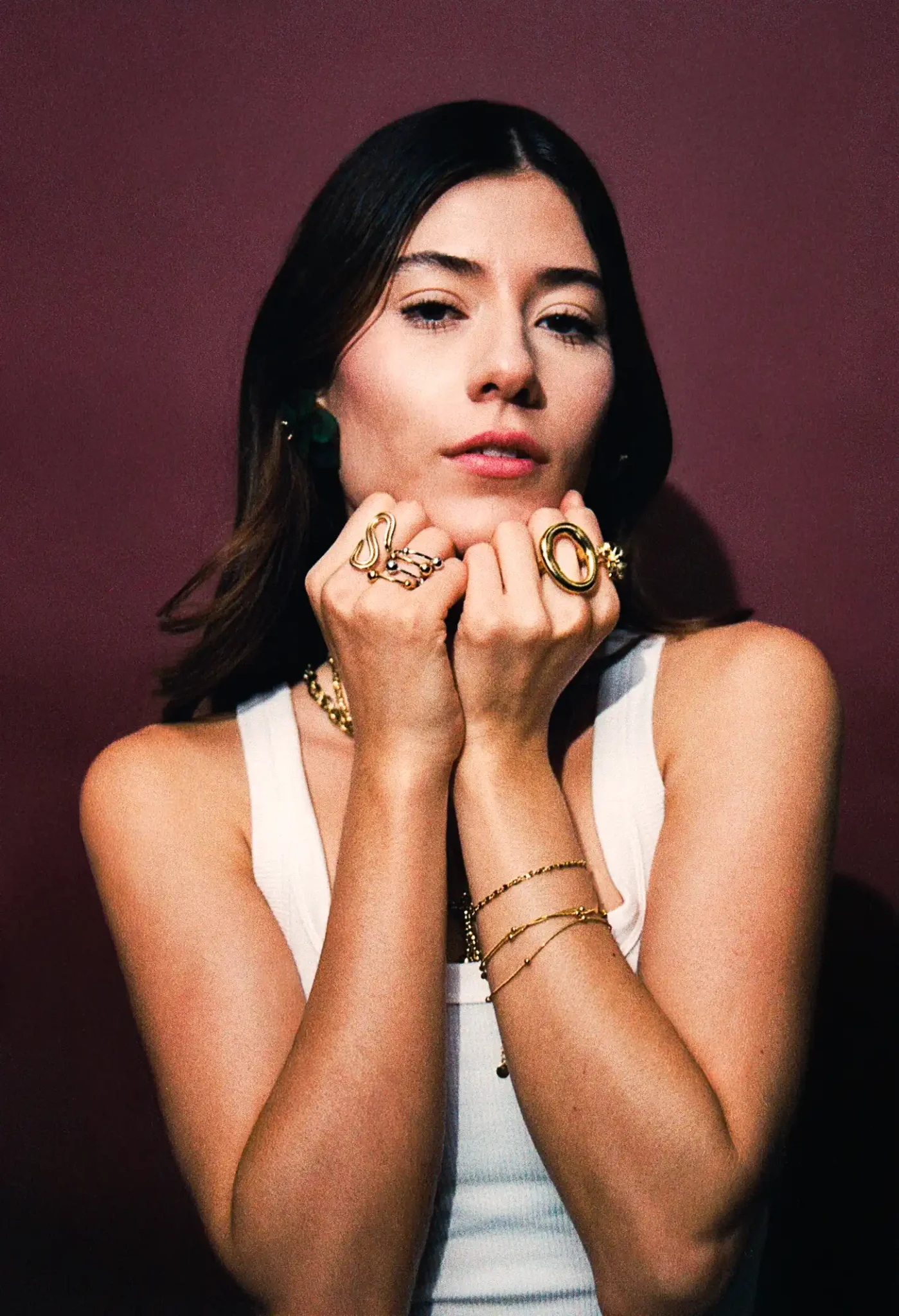 Modelo con look editorial luciendo variedad de anillos, pulseras y aretes en oro laminado, chapa de oro y acero inoxidable.